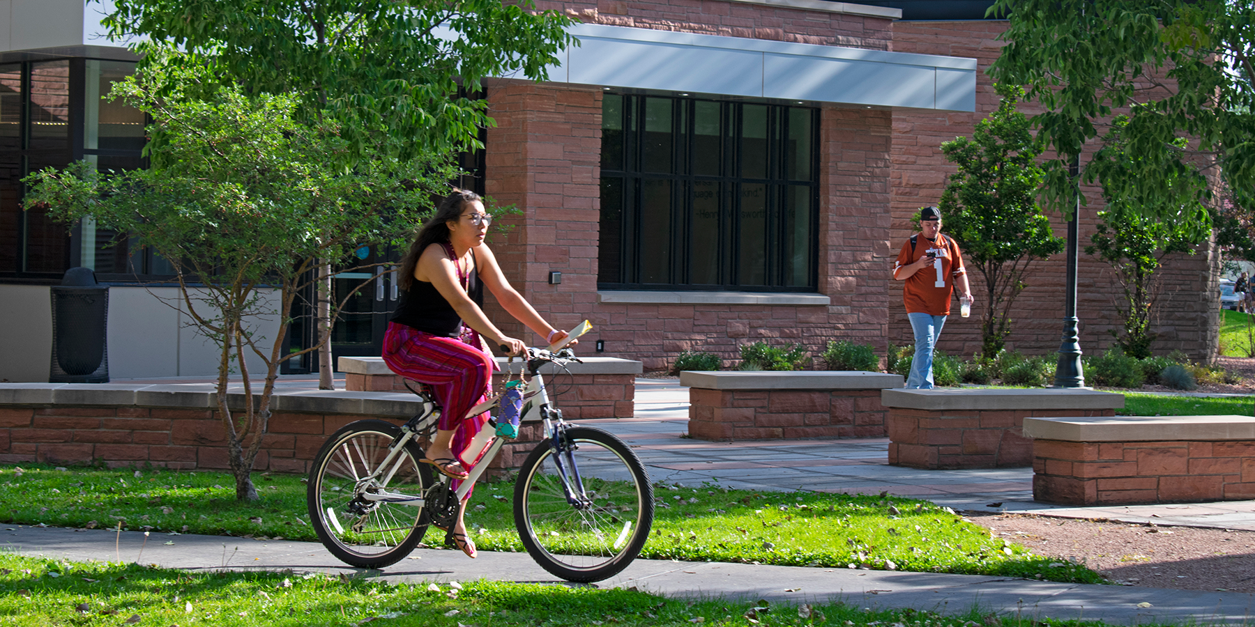 student riding a bike on campus grounds in the summer